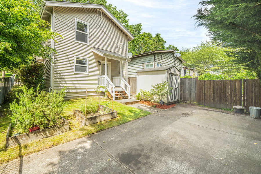 fully fenced wrap-around yard with off-street parking pad, planter boxes and mature blueberry bushes.
