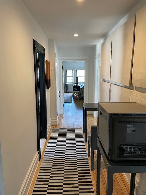 Long hallway with artist work connects living, bedroom and bath