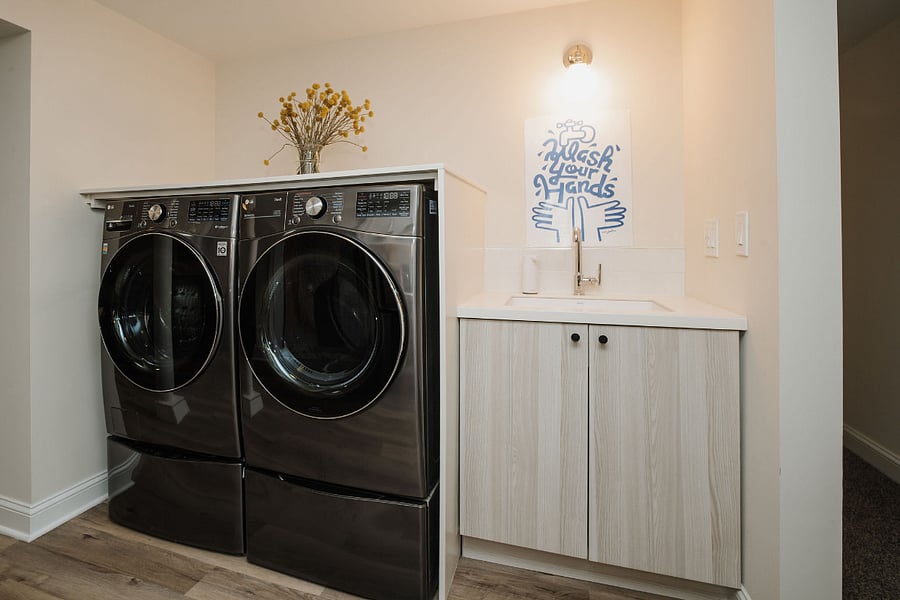 On the other half of the kitchen are the washer/dryer and utility sink with garbage disposal. Dish drying rack and cleaning supplies are inside the cabinet.