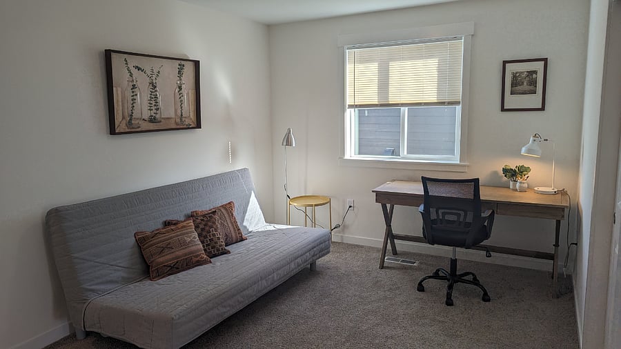 Dedicated work space with desk, office chair, and fold-out futon.