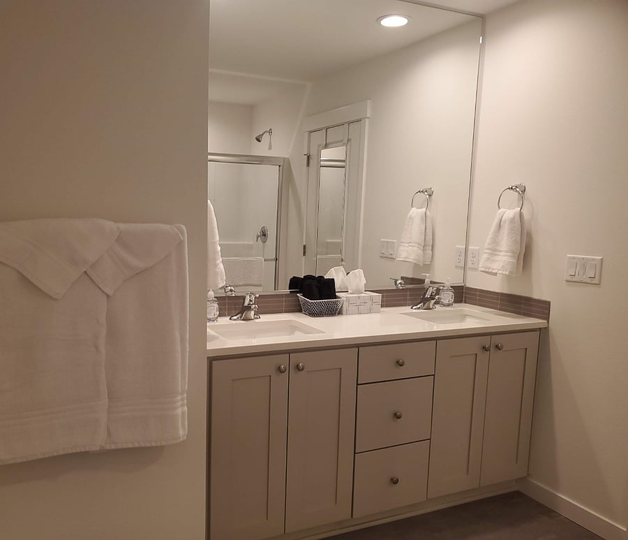 En suite bathroom with double sinks, shower, and walk in closet accompanies the primary bedroom