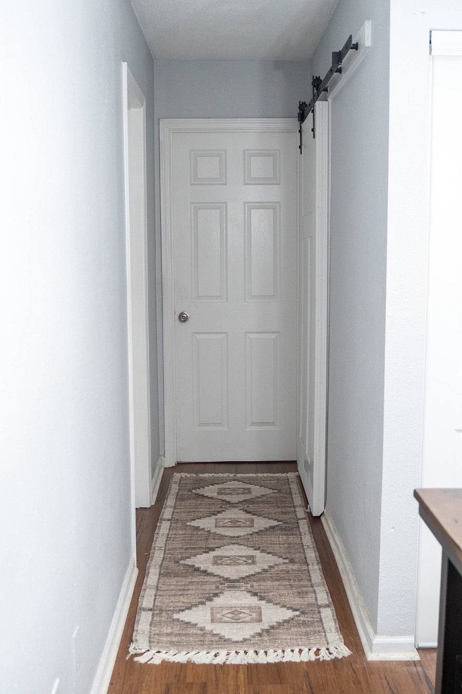 Hallway: straight ahead is the primary bedroom. On the left, is the guest bedroom, and on the right is the bathroom with barn style door.