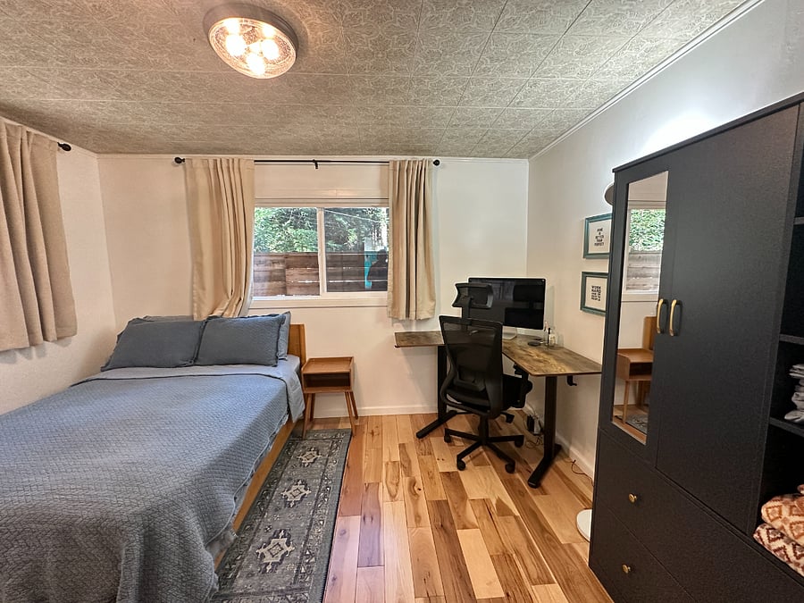 Bedroom 3 (of 4) with double size bed and office setup (complete with standing desk, wireless keyboard and mouse combo, and monitor)