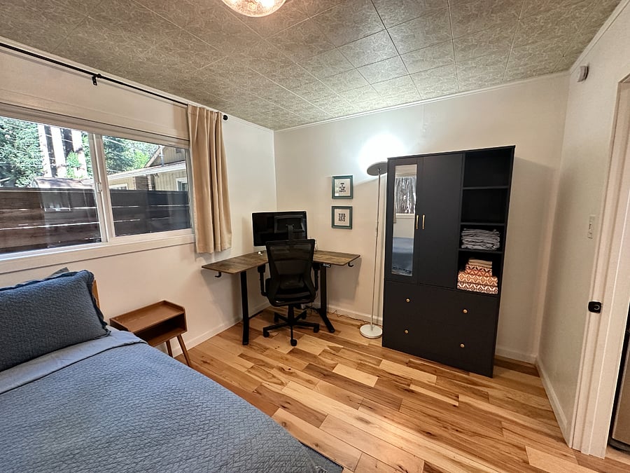 Bedroom 3 (of 4) with double size bed and office setup (complete with standing desk, wireless keyboard and mouse combo, and monitor)