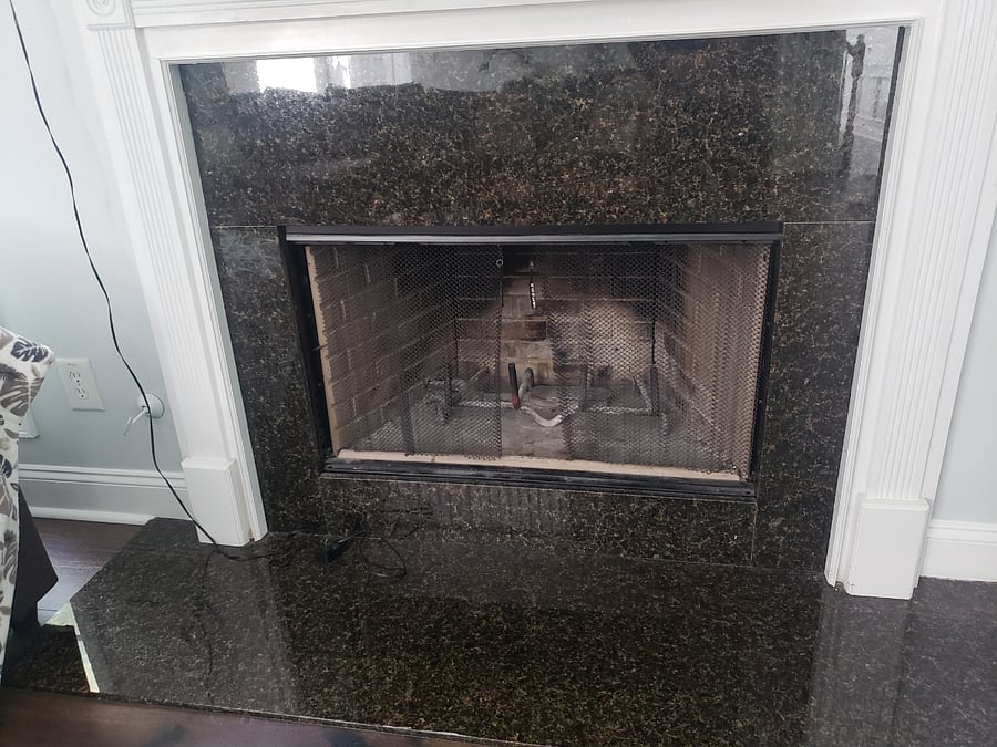 Wood-burning fireplace with gas starter and granite framing.