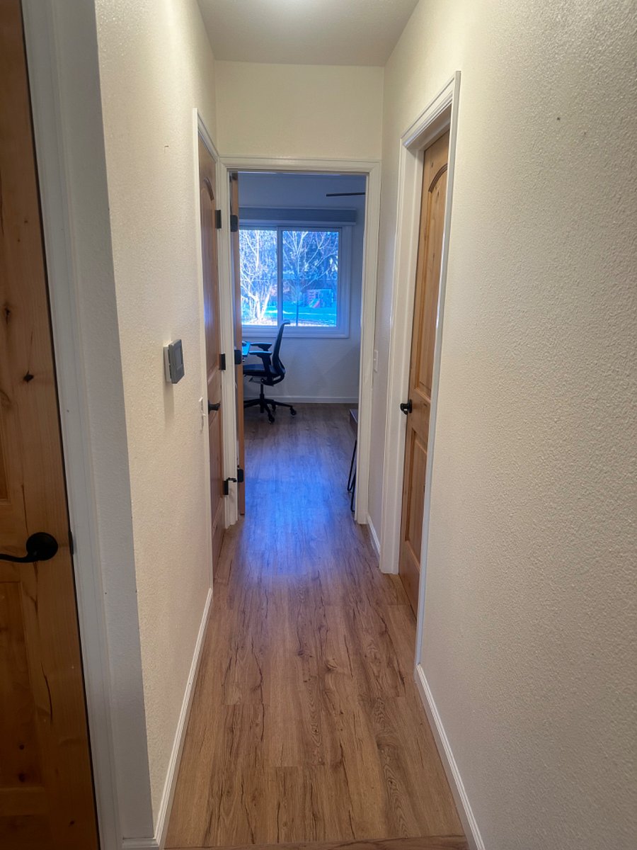 This is the hallway between the living room and the primary bedroom. door on the right is the bathroom on the left is a storage closet