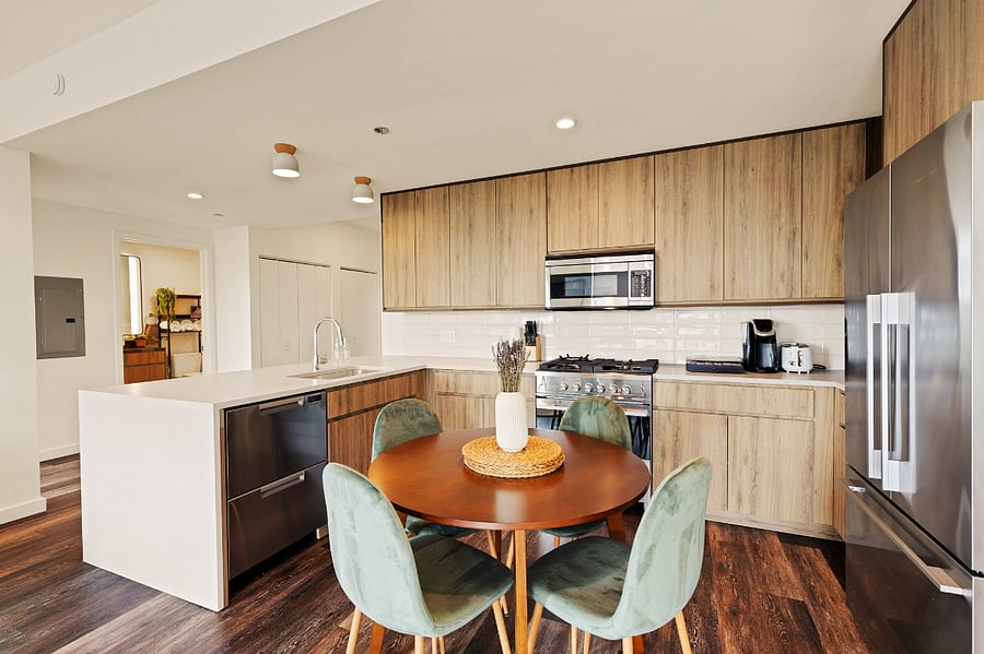 Modern Luxury Kitchen with Breakfast Bar and Dining Area- Whip up your favorite meals in this fully equipped kitchen featuring a sleek breakfast bar, modern dining setup, and elegant wood cabinetry  the perfect blend of style and function.