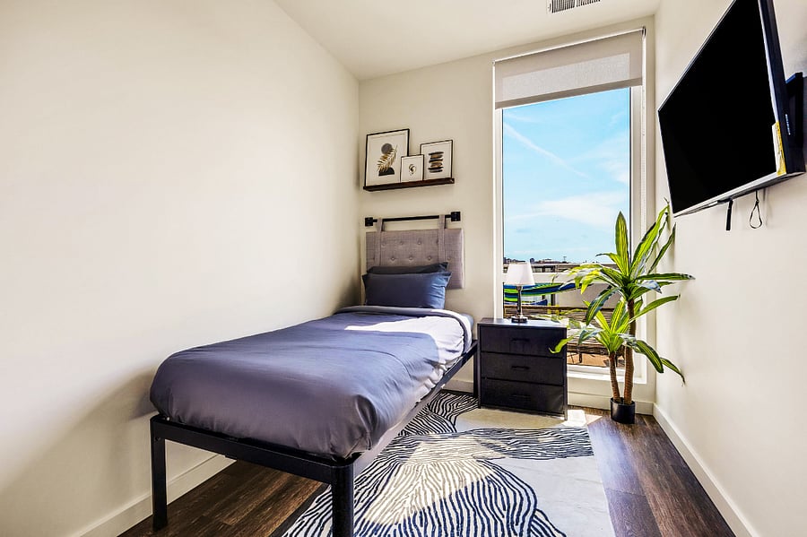 Peaceful single bedroom with city views, a cozy reading nook, and mounted smart TV  ideal for solo travelers or kids needing their own space