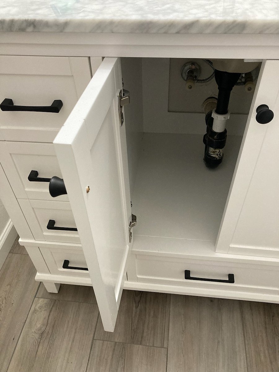 Left side under sink of bathroom vanity; yours for storage.