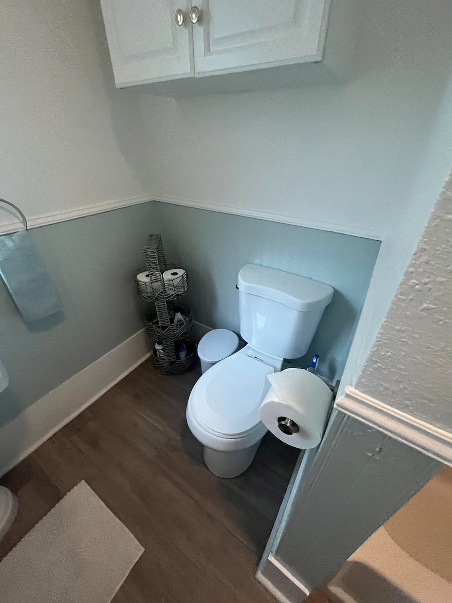Toilet and storage in main bath. Floor shelf and cabinet above toilet.