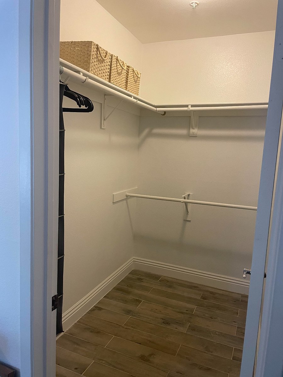 Primary walk-in closet includes storage baskets, hangers, and a rack for accessories along with a luggage rack.