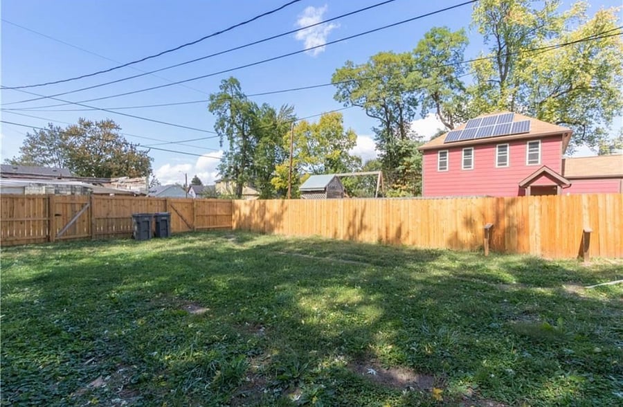 Large fenced in backyard with fire pit. 