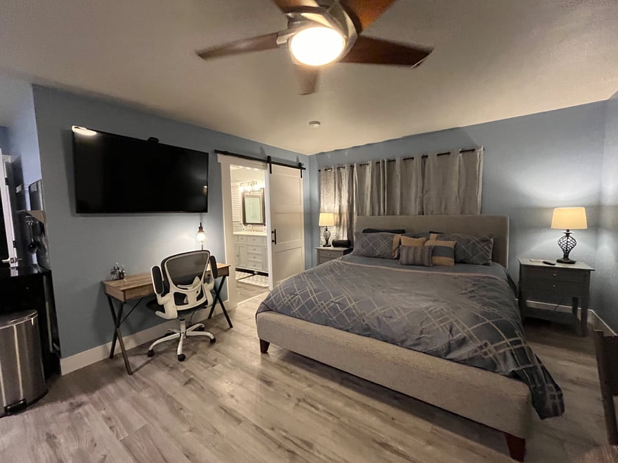 A king size bed with padded head and foot boards accompanied by twin two-drawer night stands and a 55" smart TV stand ready to usher you into vacation mode.