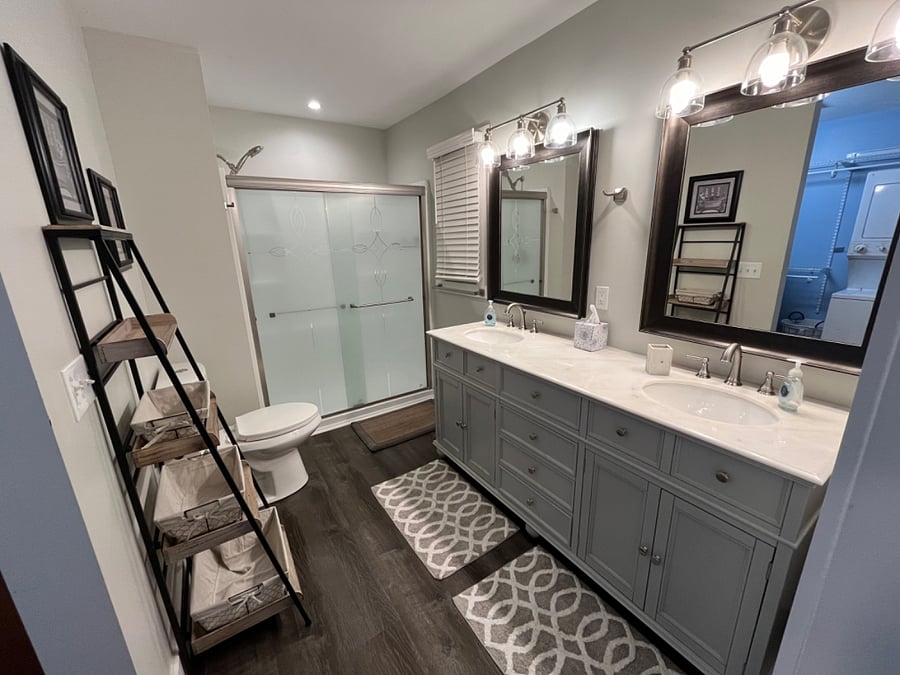 A barn door invites you into this oversized bathroom that boasts a double sink vanity with lots of drawer and under-sink storage, as well as a walk-in shower.