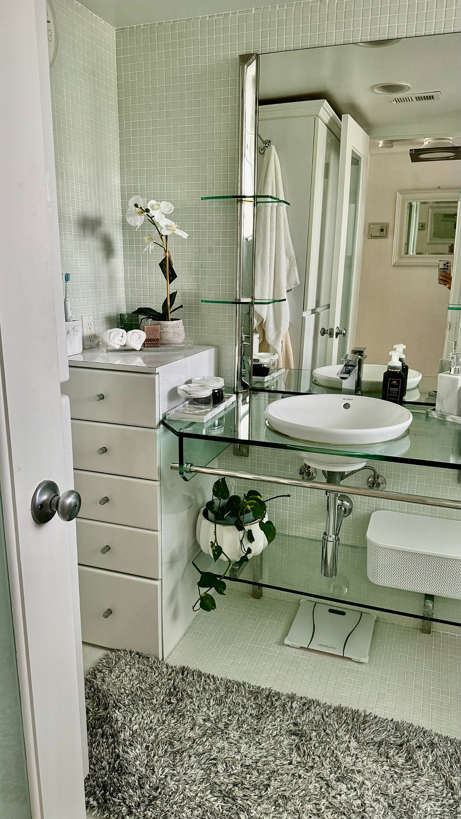 Beautiful white and glass bathroom with ample storage.