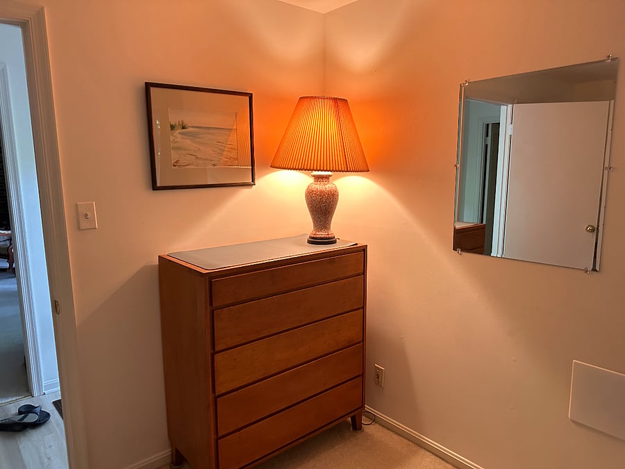 On right as bedroom is entered is the dresser, light on wall switch, and mirror.