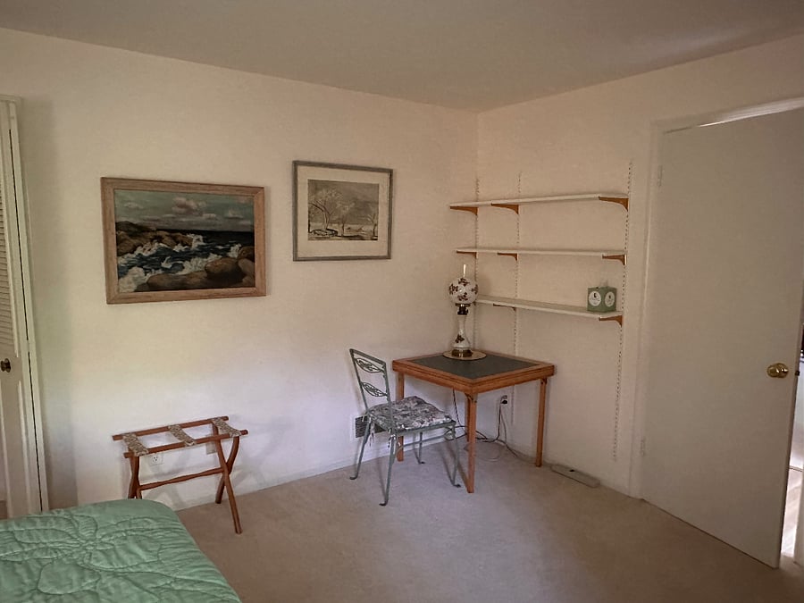 Interior wall of bedroom with lamp, desk, chair, and shelves.