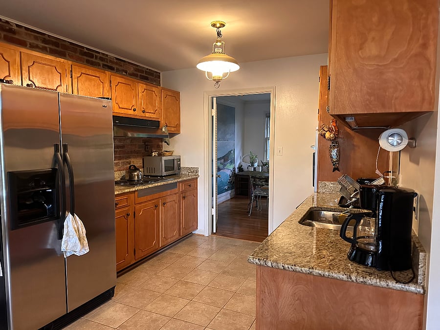 Closeup of kitchen showing refrigerator, stove top, and microwave. Plates, cups, pots, pans, bakeware, silverware, mixing bowls, etc., provided.