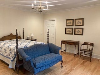 BR2: double bed, sitting area with desk, chair, love seat, wingback chair, dresser, large closet & northern view of private wooded setting.