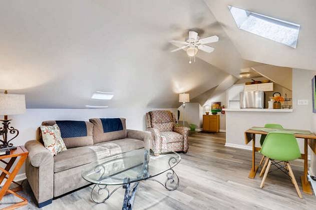 View of living room showing dining table, sofa, recliner, and bar at the kitchen.