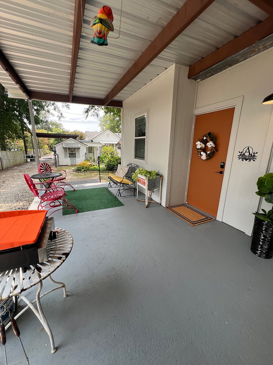 Auto gate in the background. Huge covered furnished outdoor living area with a tv, comfy seating and a table for outside dining to relax under the string lights after a long day.