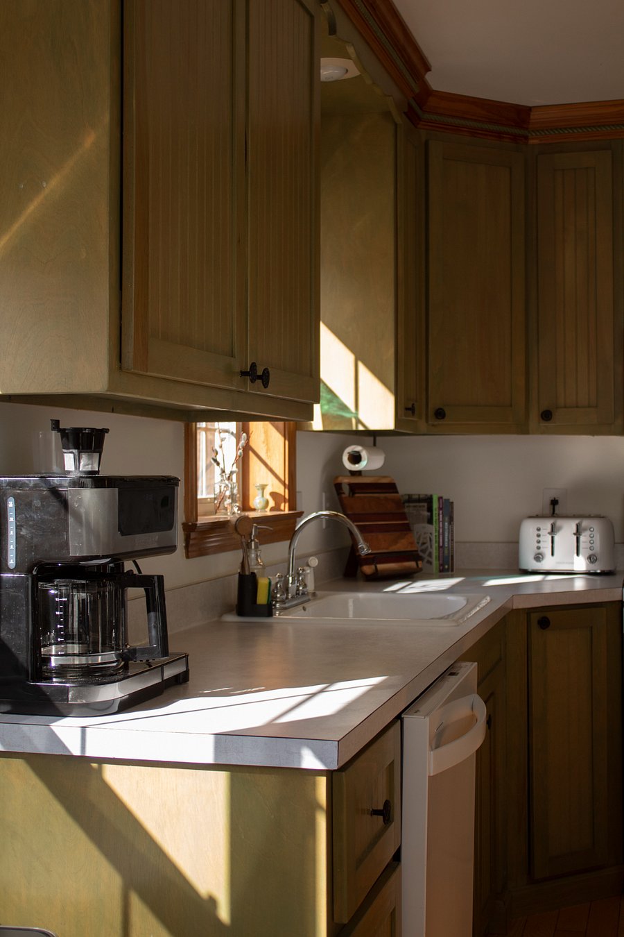 Kitchen counter with one cup and full pot coffee maker.