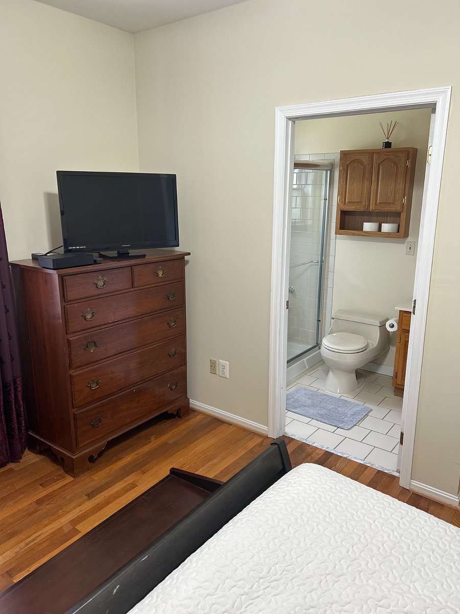 Rensselaer Room -large chest, TV and hardwood floors, entrance to ensuite bathroom.