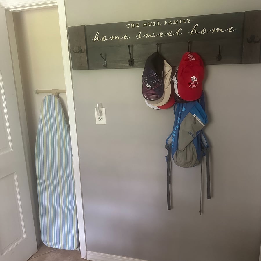 Laundry room includes ironing board, iron with steaming and hat rack