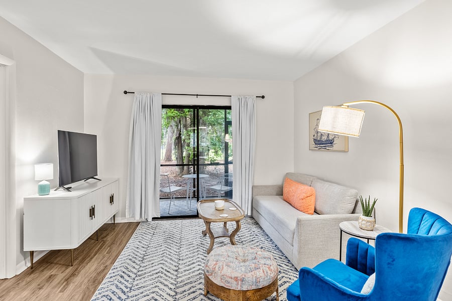 The living room offers a cozy seating area, a smart TV, and access to a private screened porch with tranquil outdoor views.