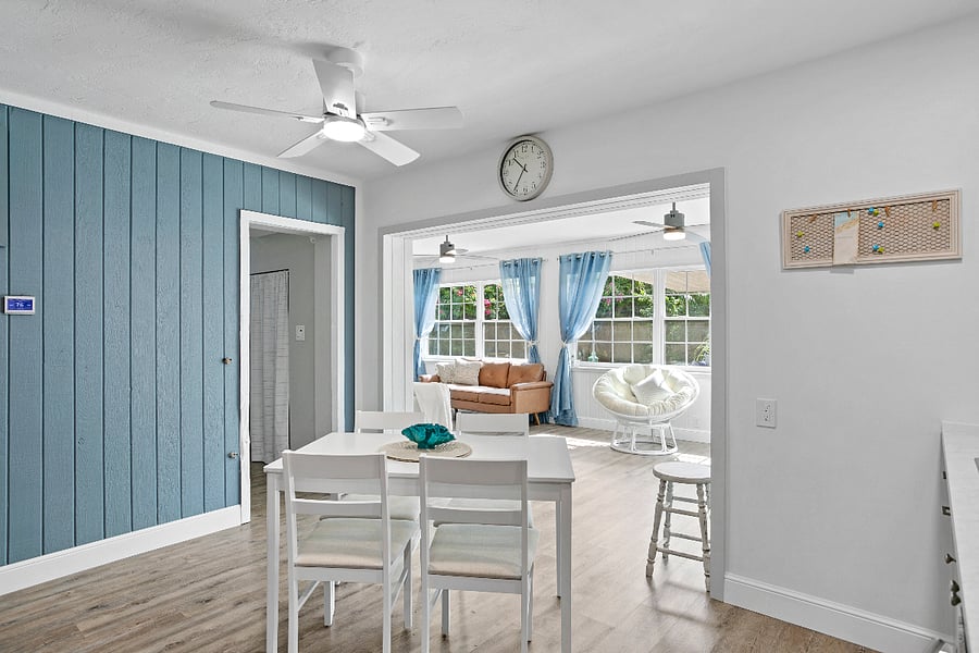 Open concept kitchen/living room with plenty of natural light overlooking mature landscaping and relaxing pool view.