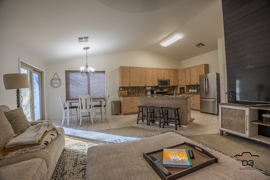 Open livingroom to kitchen with dining table and bar seating on kitchen island