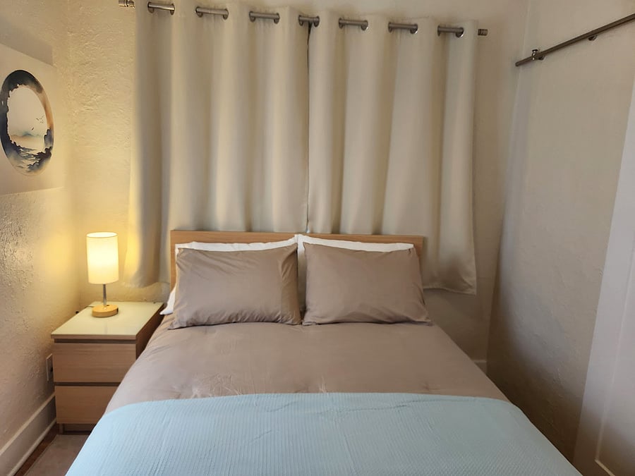 The bedroom with its full size bed and medium-firm mattress features black-out curtains, cotton bedding and a touch-lamp with different settings and charging ports.
