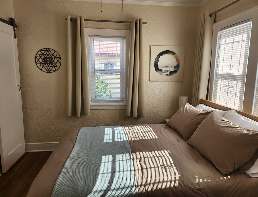 The bedroom is to the right of the living room. It is decorated in a calming color scheme and features art from all over the world. For storage there are a closet, a nightstand with two drawers, and two large under-bed drawers perfect for seasonal items and extra bedding.