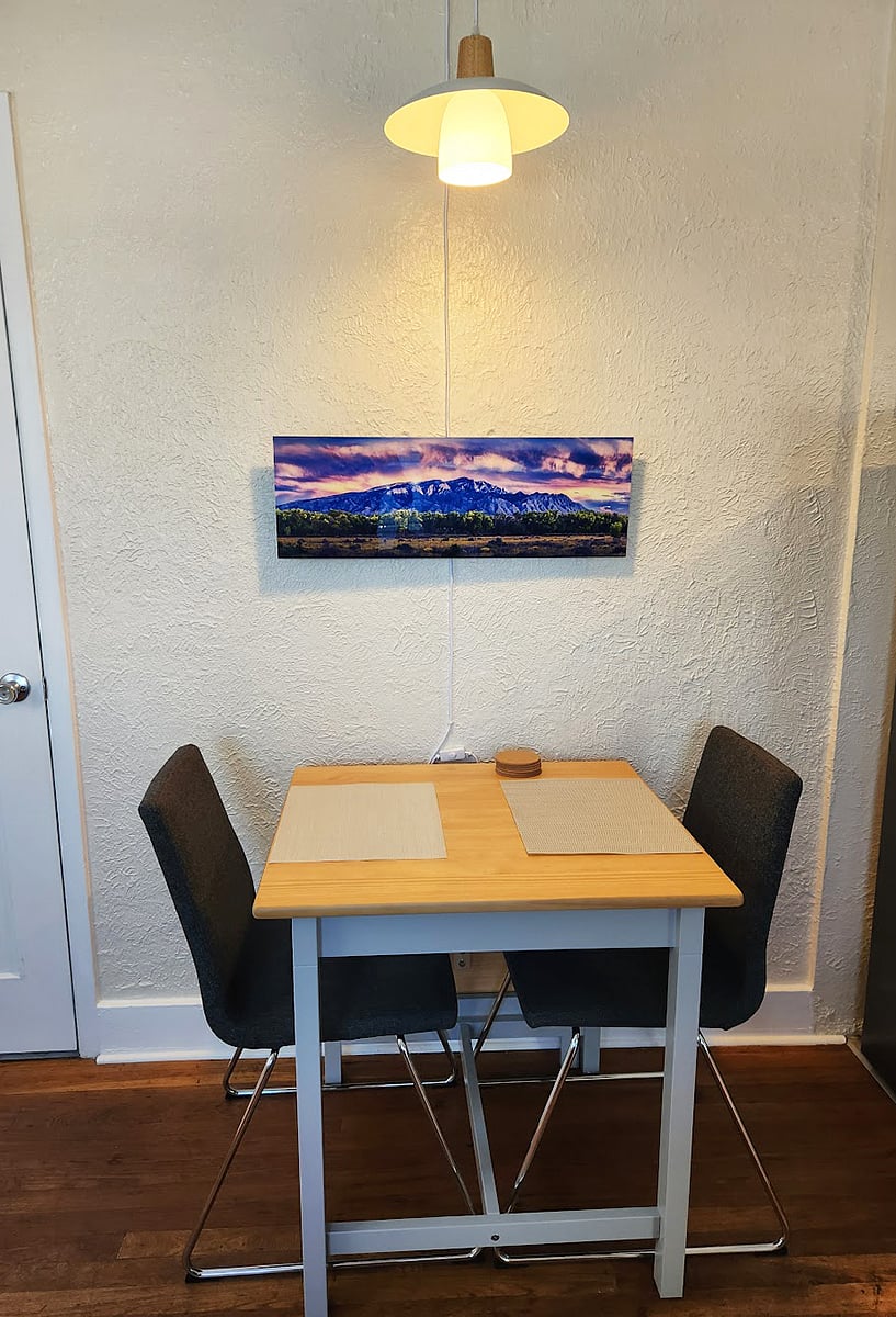 The art above the dining area is by local artist Allan Morrison and features the a lovely view of the Sandia Mountains and the Bosque. Atop the dining area is modern glass and wood swag lamp.