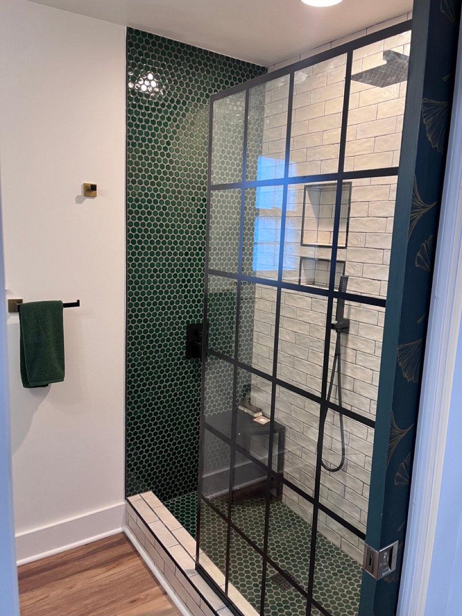 Walk in tiled shower with glass wall and a rain head shower.  Outfitted with hand-held spigot as well as small corner bench for your shower needs.
