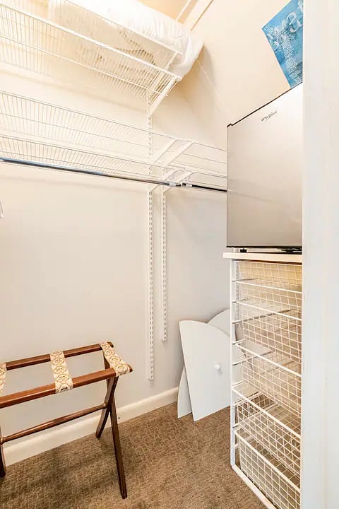 Large walk-in closet with beverage fridge, ironing board and Iron.