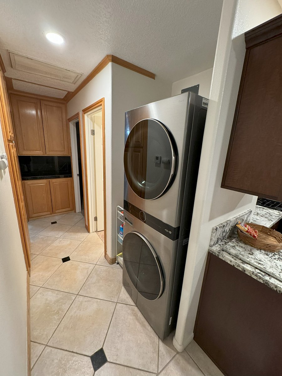 Hallway has Stackable Full Size Washer / Dryer with Utility Cart with Starter Supplies. Maple Double Cabinet at end with Granite Counter Top and Large Double Maple Pantry