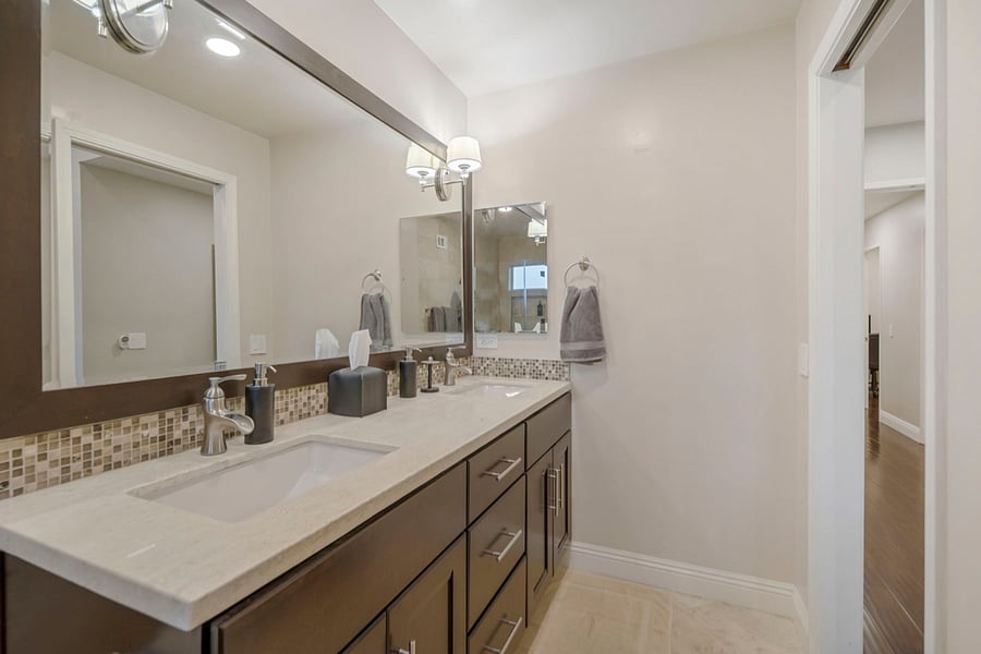 Each person can comfortably use their own sink and countertop space for personal items. The expansive mirror allows both to get ready simultaneously, enhancing efficiency and convenience in the morning routine. 
