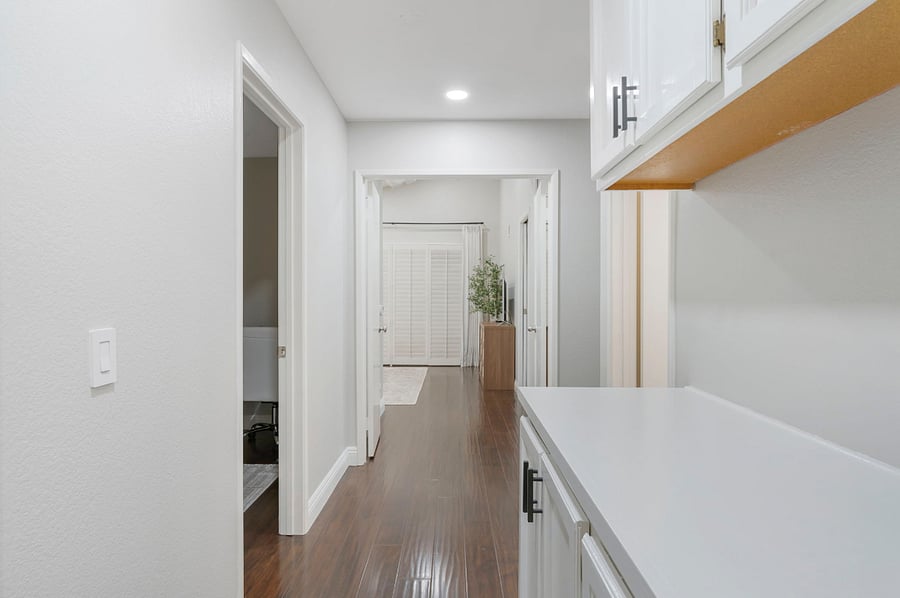 The hallway between the bedrooms and the second bathroom features ample cabinets for storage. The clean, functional space provides easy access to the iron and ironing board, while keeping the area tidy and organized.