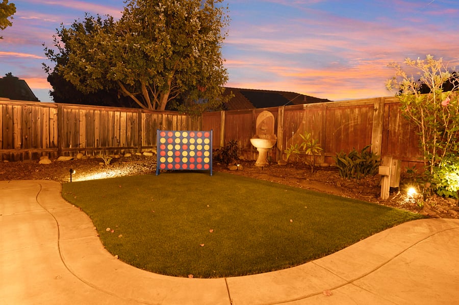 A large Connect Four game on the backyard turf offers endless fun. The vibrant, oversized game board stands out against the green grass, inviting players to strategize and compete. Perfect for family gatherings and friendly outdoor challenges.