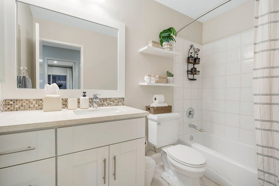 This bathroom is equipped with a tub and a shower, offering both relaxation and convenience. Shampoo, conditioner, and body wash &  plush towels are available for guests, providing a complete and comfortable experience.