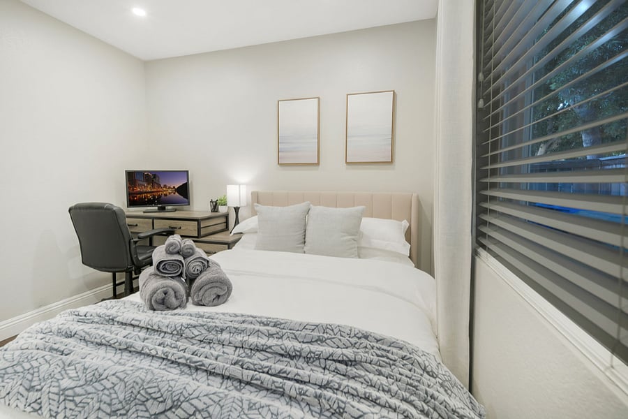 This bedroom features a desk perfect for productivity, paired with a laptop and monitor for dual-screen convenience. An ergonomic office chair ensures comfort during long work sessions, creating an ideal workspace within the cozy bedroom setting.
