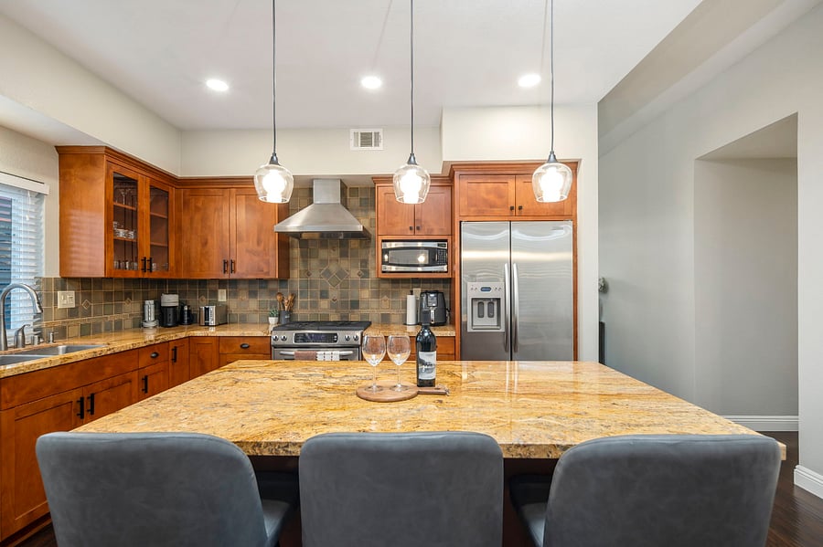 The modern kitchen boasts a spacious island with bar stools.  Its equipped with a Nespresso machine, air fryer, blender, electric kettle, and a full set of cooking utensils, offering both style and functionality for any culinary needs.