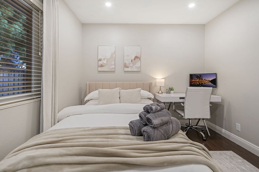 This bedroom workspace includes a sleek desk with a laptop monitor, providing an efficient setup for work or study. An ergonomic office chair adds comfort & support, making this corner both functional & stylish, perfect for a productive environment.