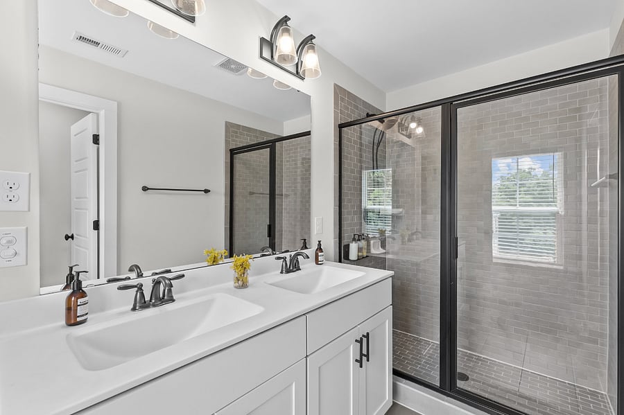 Master bathroom with walk in shower, dual sinks, and separate toilet area