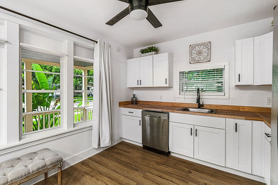 Spacious kitchen with large windows looking out over massive front porch and lush green traveler palms. Full appliances, french door refrigerator, dishwasher, microwave, coffee maker, blender, silverware, plates and general appliances.