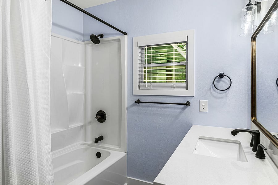 Common bathroom with bathtub and large vanity.