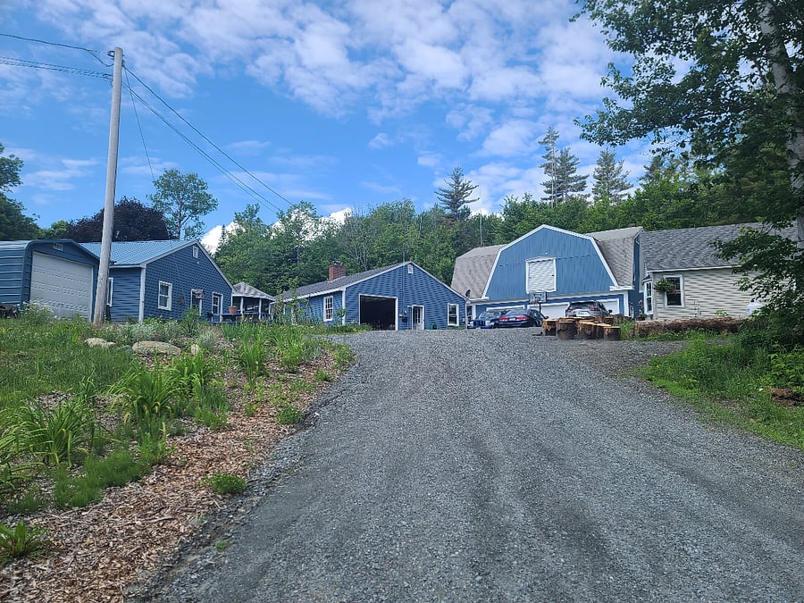 View coming up the driveway. The guest cottage is to the left. Moving to the right is the garage for the main house (which is attached behind the garage), the big garage at the top of the hill, and the cottage on the right has a full-time resident.