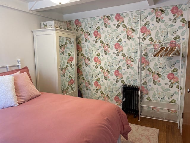 For storage, the bedroom has a Pottery Barn wardrobe and an external clothes rack for storage. The wall paper is Anthropology Peonies and Butterflies.