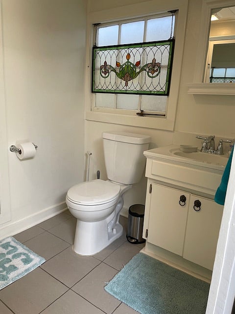 Cottage style cabinet and stain glass over the bathroom window.